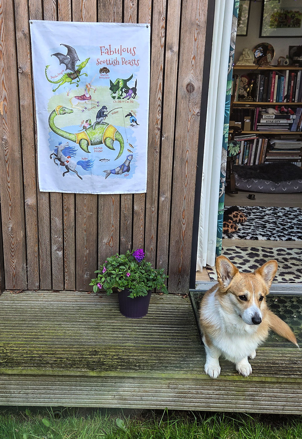 Tea towel with images of fabulous Scottish beasts including the Loch Ness Monster, Kelpie and Selkie. A corgi is sitting below the tea towel.
