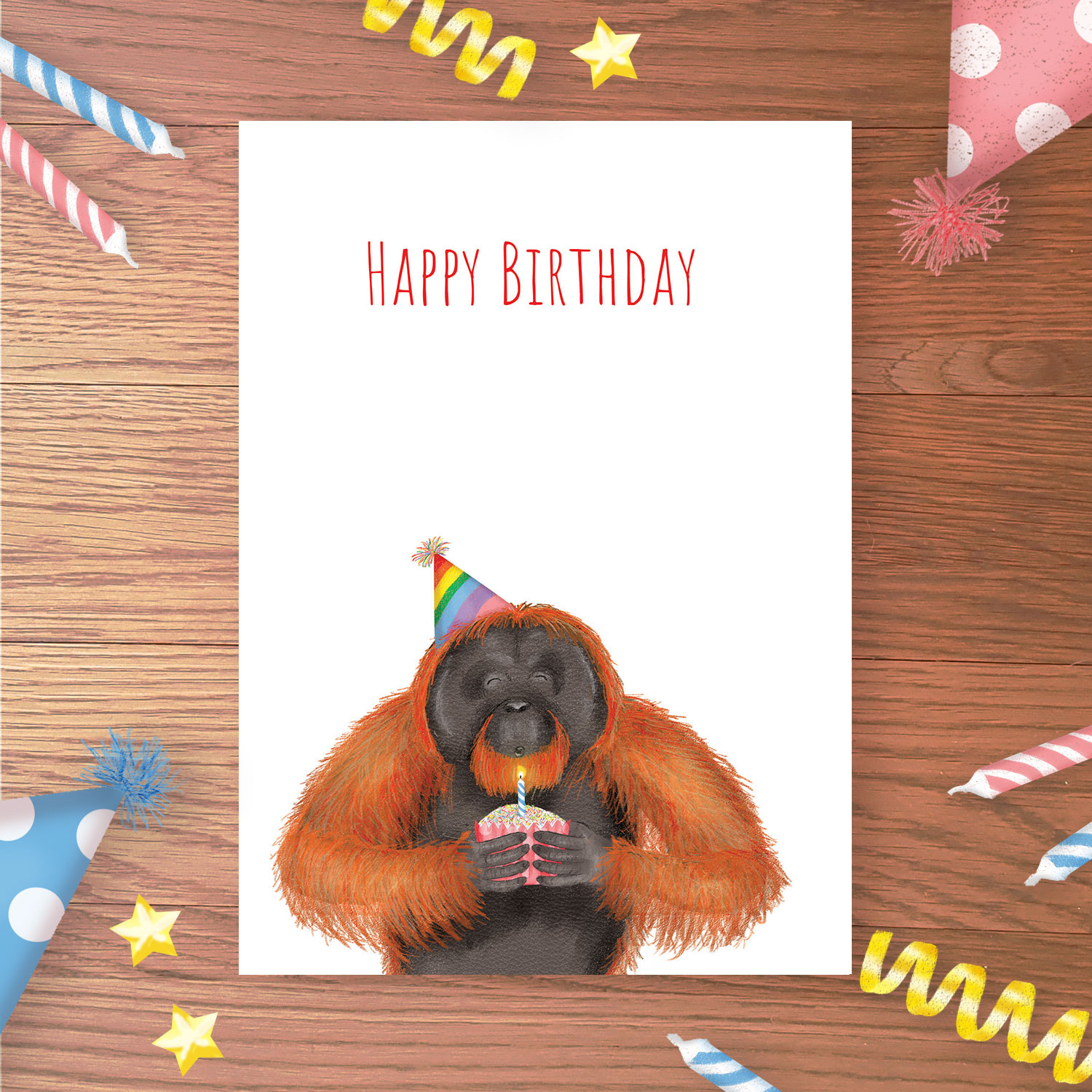 Birthday card with an orangutan wearing a rainbow party hat, blowing out a candle on a cake.