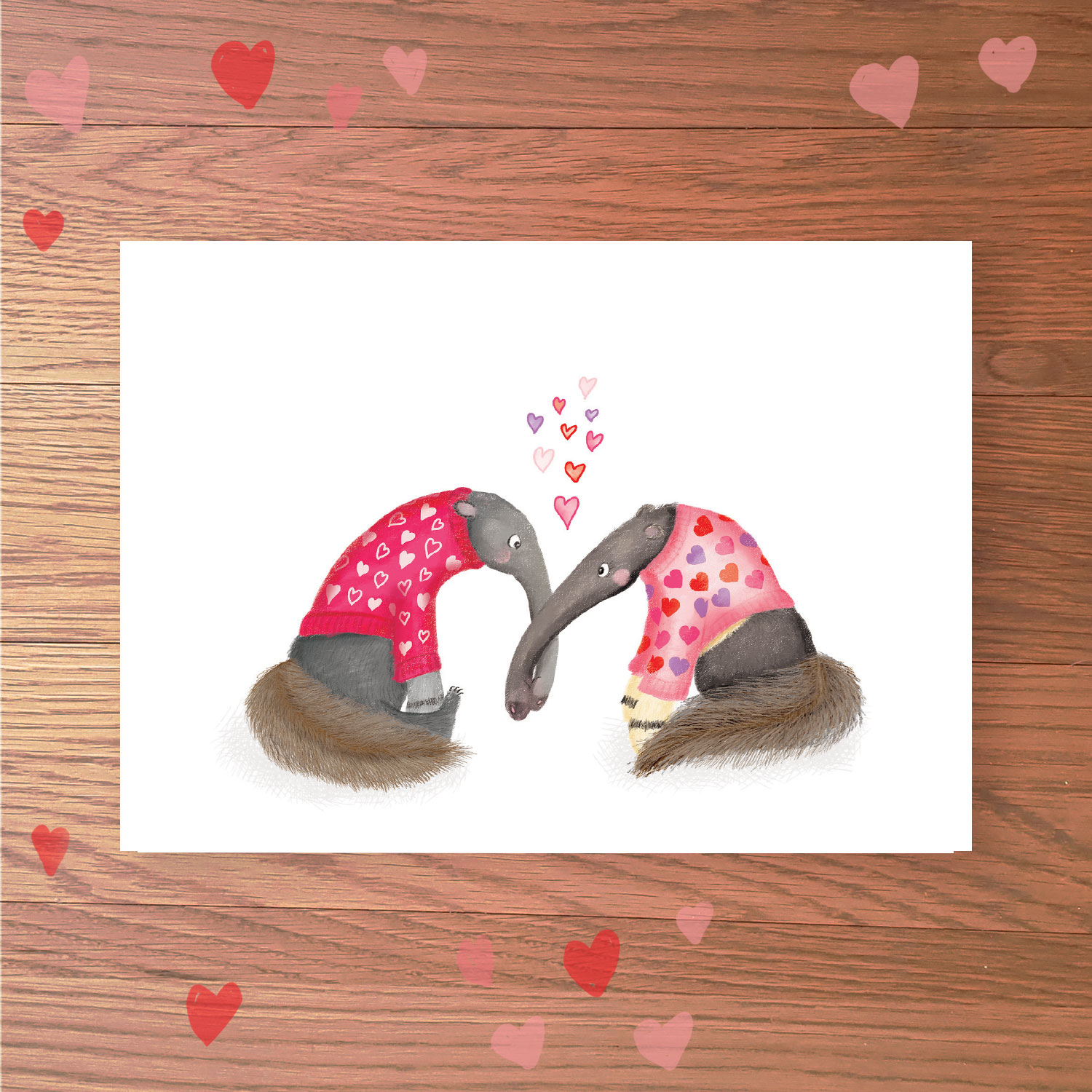 Greetings card with two anteaters wearing pink heart-patterned jumpers, with their snouts entwined.