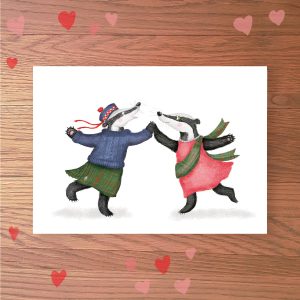 Greetings card with two badgers dancing a ceilidh together. One is wearing a Glengarry hat, knitted jumper and kilt and the other is wearing a pink dress with a tartan sash.