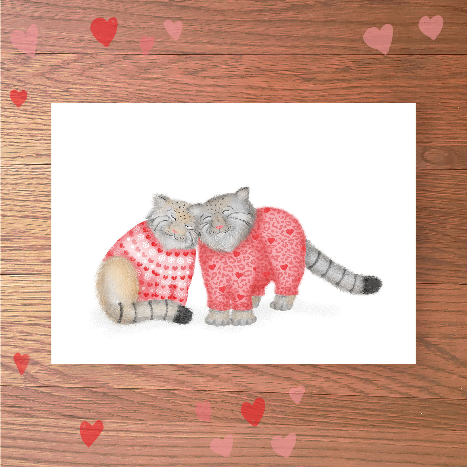 Greetings card with two Pallas's cats wearing pink heart-patterned jumpers rubbing their heads together.