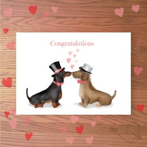 Greetings card with two dachshund dogs dressed as grooms, with Congratulations written above.