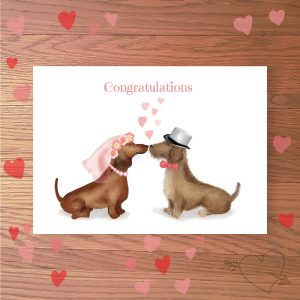 Greetings card with two dachshund dogs dressed as a bride and groom, with Congratulations written above.