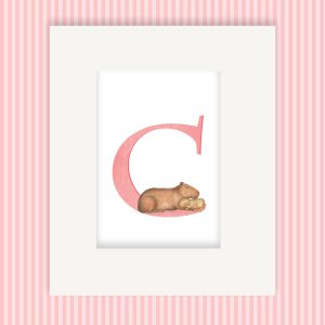 Mounted print hanging on a wall, with a pink capital letter C with a cute mother and baby capybara.