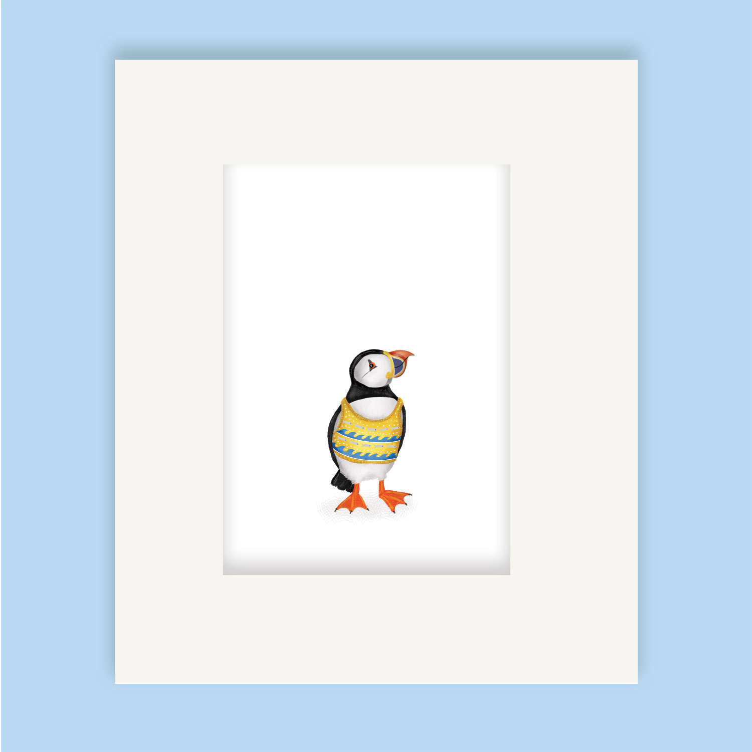 Mounted print hanging on a wall, of a puffin wearing a yellow and blue knitted tanktop.