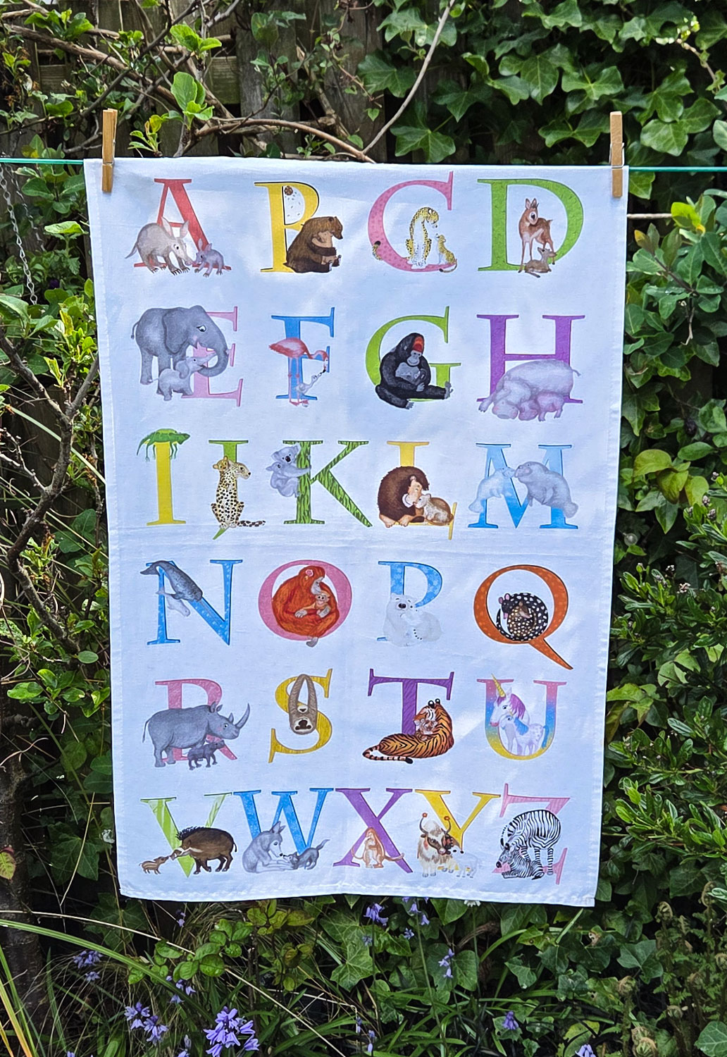 Tea towel with a colourful alphabet illustrated with baby animals and their parents.