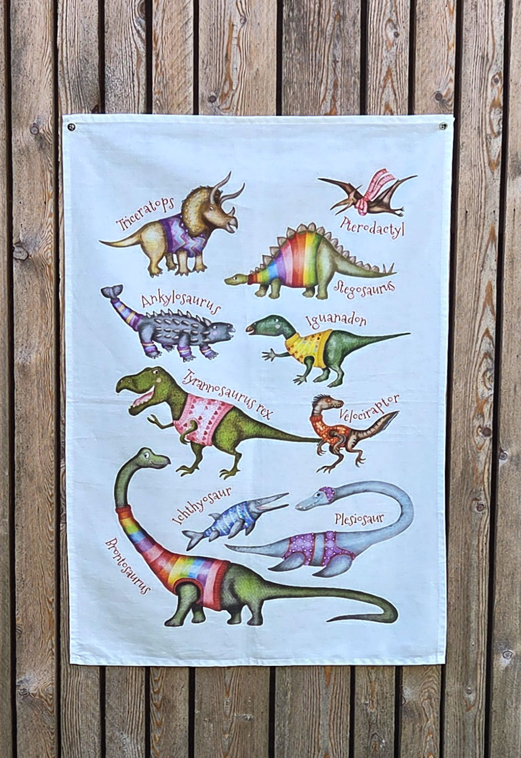 Tea towel with dinosaurs wearing colorful jumpers.