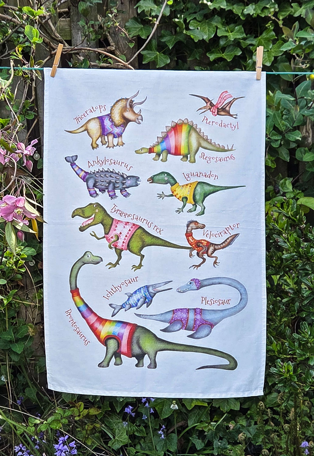 Tea towel with dinosaurs wearing colorful jumpers.