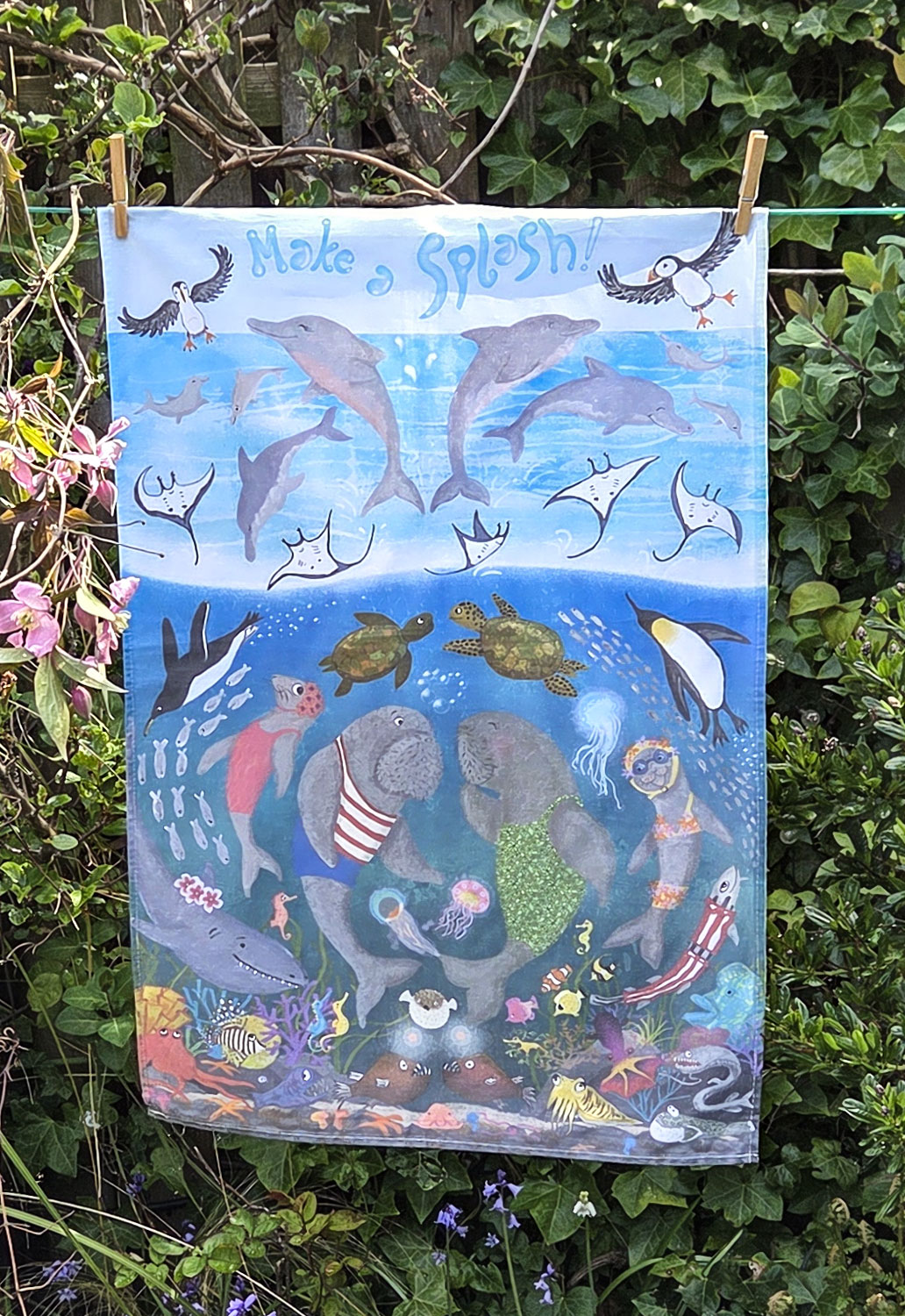 Tea towel with an underwater design of dolphins, puffins, penguins, dugongs and other sea creatures.