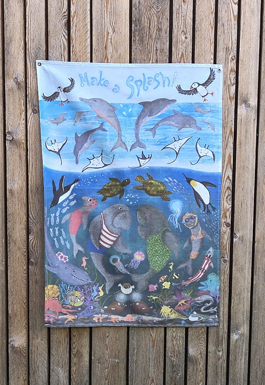 Tea towel with an underwater design of dolphins, puffins, penguins, dugongs and other sea creatures.