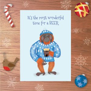 Greetings card with an orangutan wearing a blue Christmas jumper, holding a pint. Above is written It's the most wondeful time for a BEER.