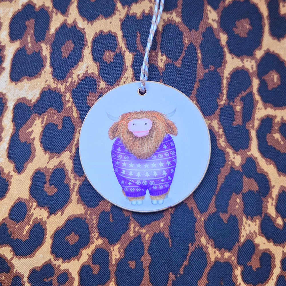 Hanging decoration featuring a Highland cow wearing a purple jumper,